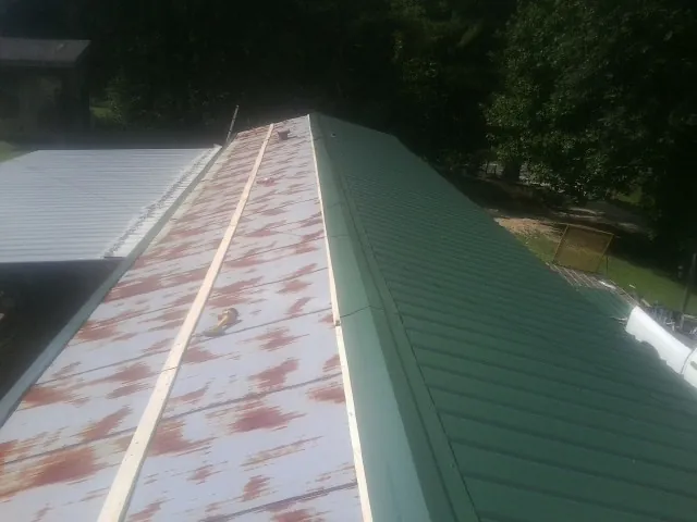 Old rusted panels beside newly installed green metal roofing — Wind Damage Roof Repair by Roofing Brothers in Coalmont