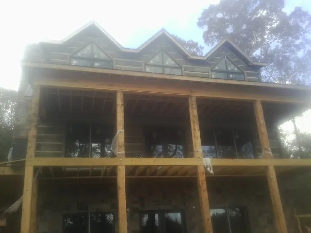 Dormers and porch framing on a large log home under construction — Roof Coating work by our crew in Coalmont