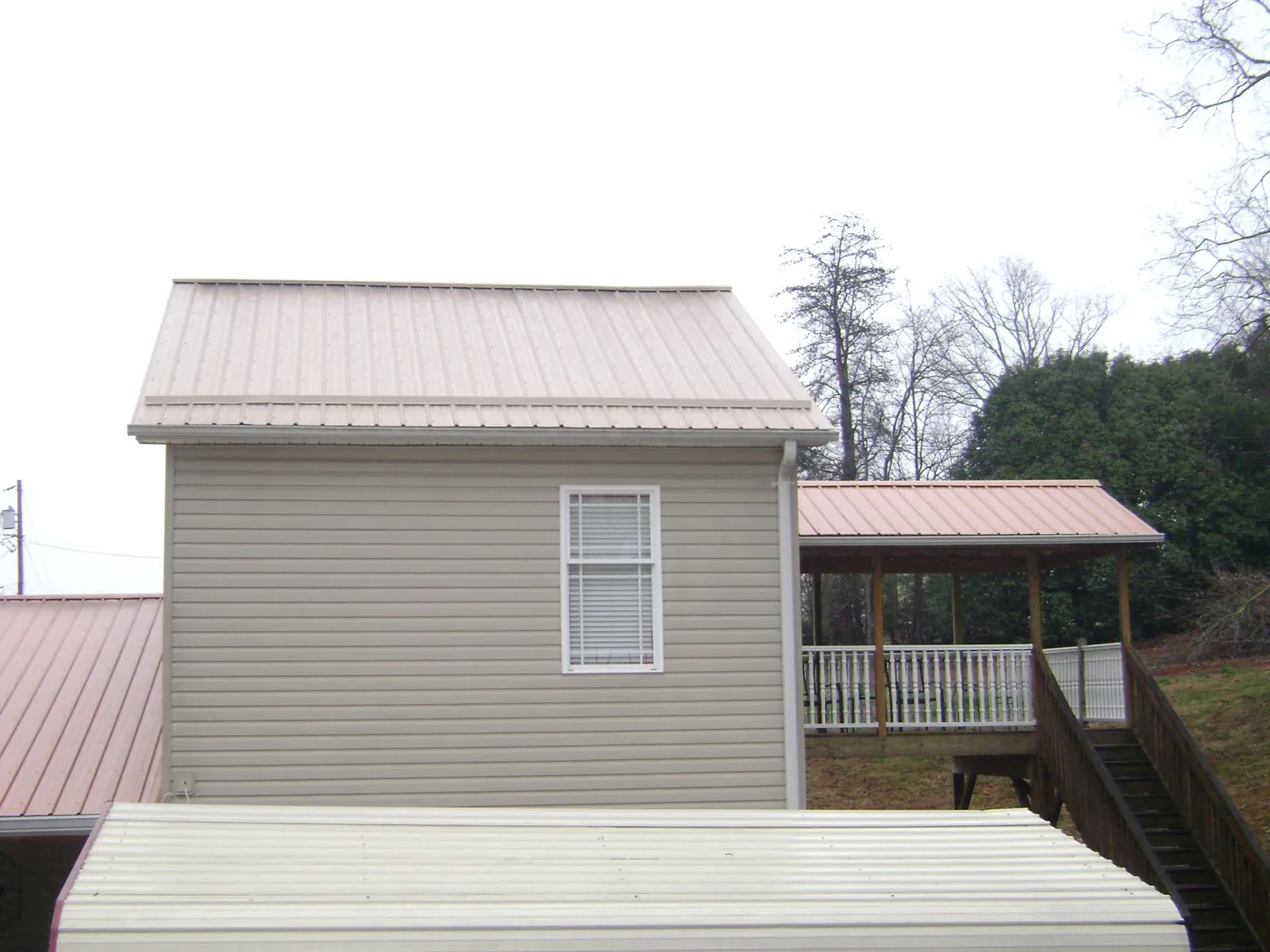 Tan metal roofs on a two story addition and attached porch, from a Roof Replacement job in Coalmont