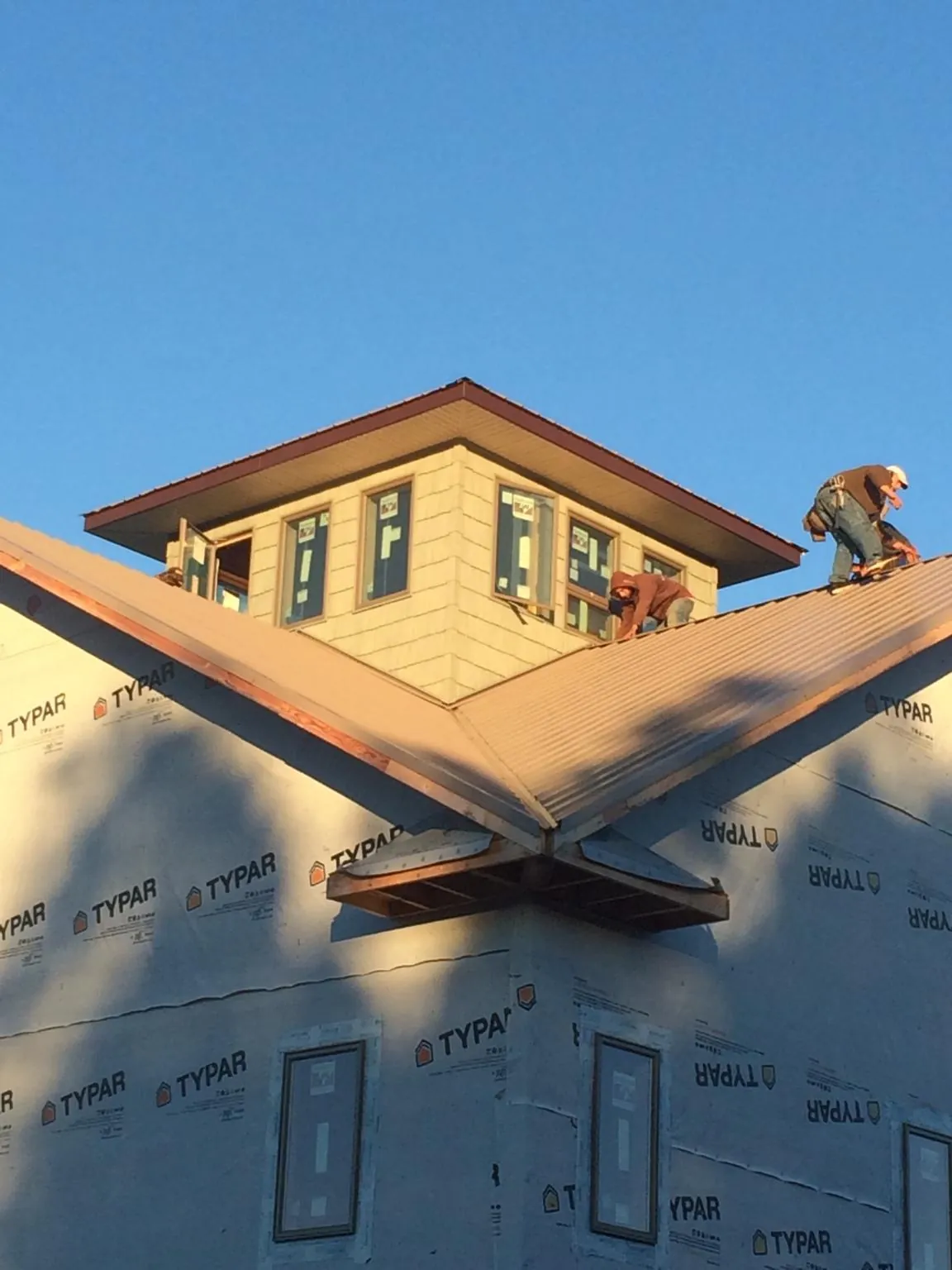 Roofers working around a rooftop cupola on a new metal roof at sunset — Roof Waterproofing in Coalmont by Roofing Brothers